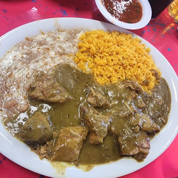 A plate of Sergio's Mexican Restaurant's pork chile verde, refried beans, and yellow rice.
